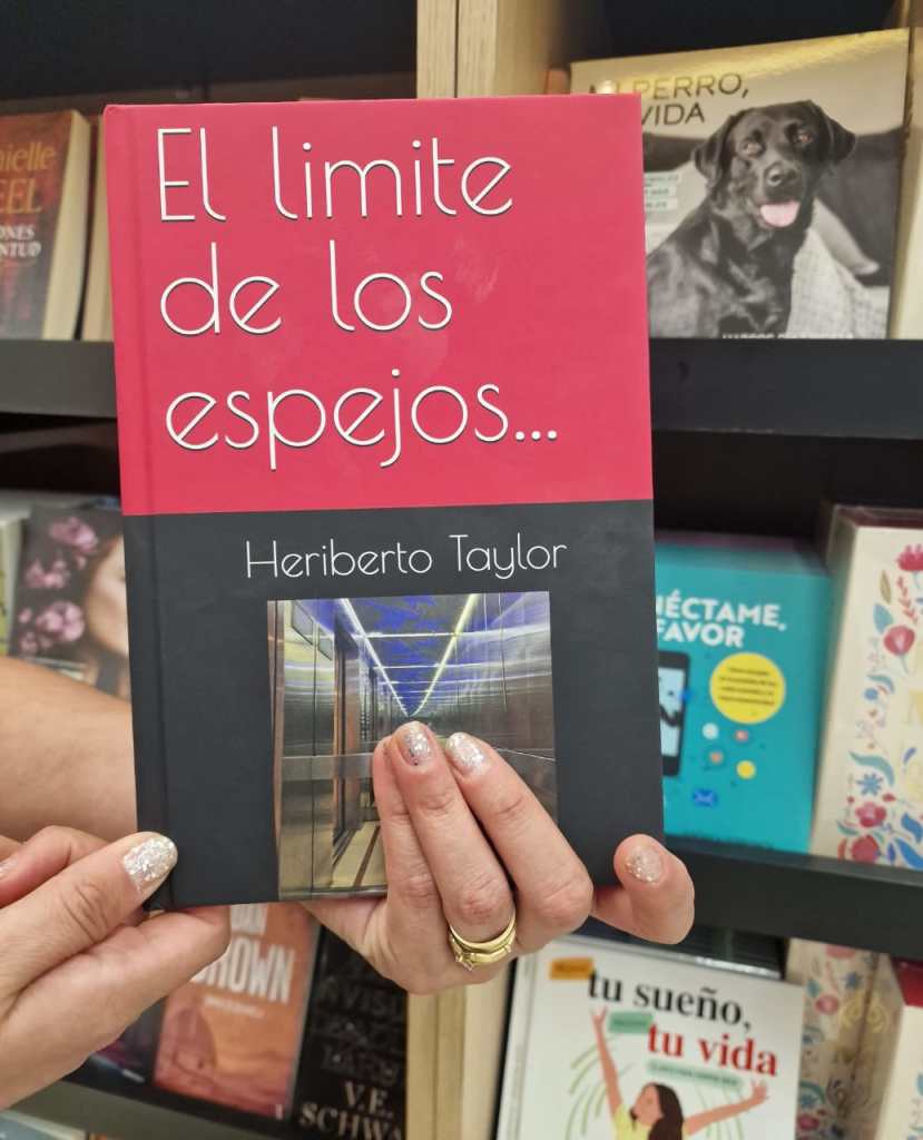 A person holding the book 'El limite de los espejos...' by Heriberto Taylor, featuring a colorful cover with a photograph of a corridor.